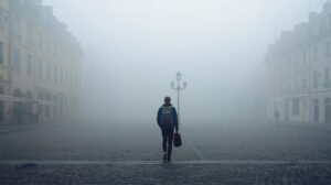 a minimalist backpacker walking through a quiet european town, surrounded by soft morning fog.